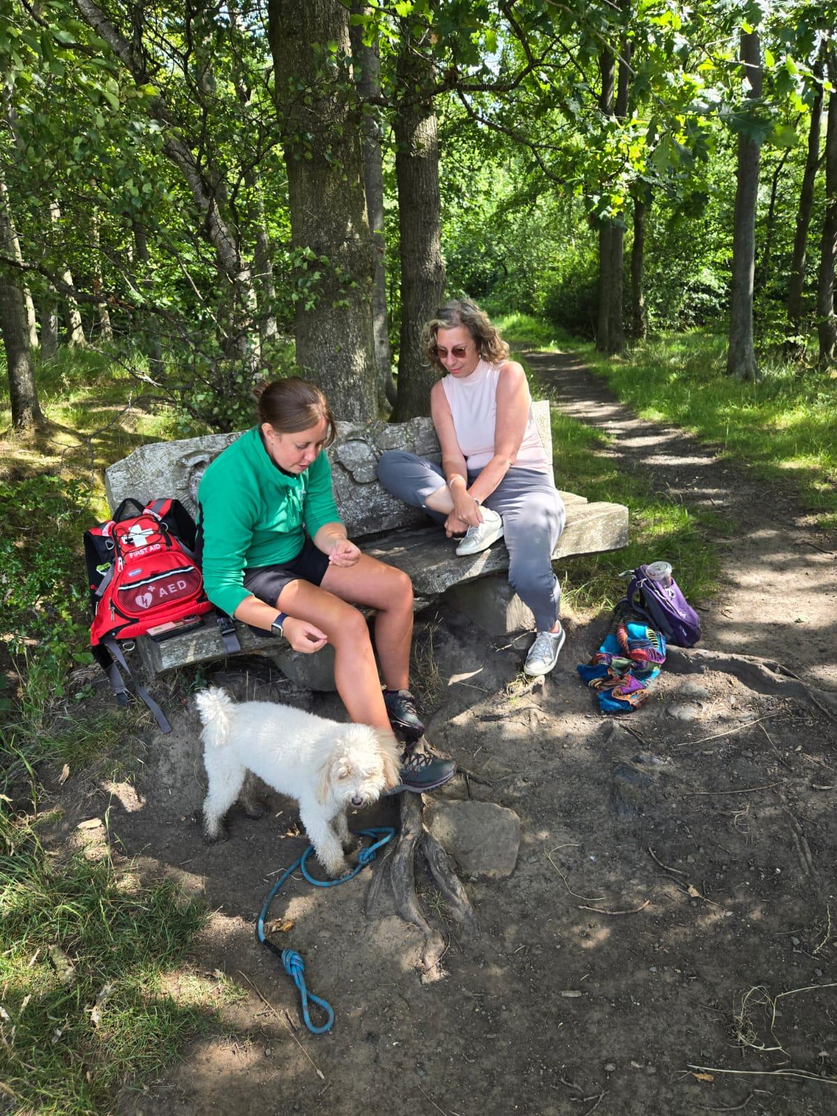 Grief educator offering emotional support to grieving client sitting on a bench with their dog